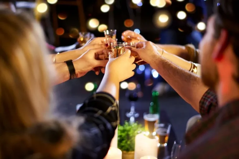 Group of friends clinking shot glasses during a night out at a cozy bar with ambient lighting